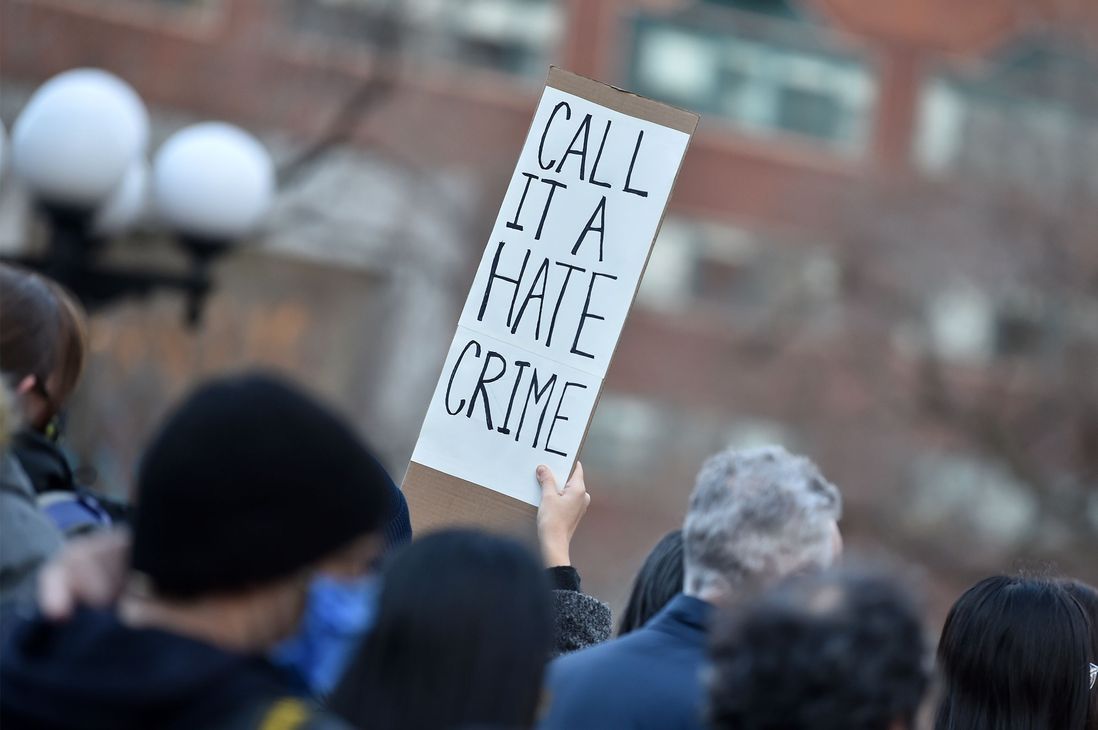 A person holds a sign that says "Call it a hate crime"
